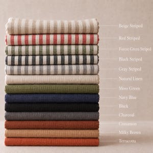 Może przedstawiać: Stos złożonych pr&oacute;bek tkanin w r&oacute;żnych kolorach i wzorach, oznaczonych jako Beige Striped, Red Striped, Forest Green Striped, Black Striped, Gray Striped, Natural Linen, Moss Green, Navy Blue, Black, Charcoal, Cinnamon, Milky Brown oraz Terracotta.