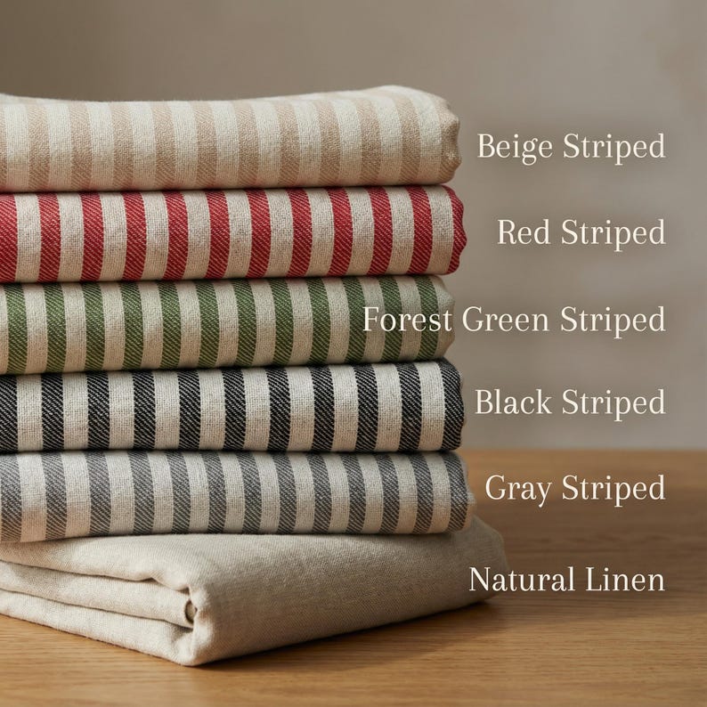 May include: A stack of folded fabric samples in various colors and patterns. The samples include beige, red, forest green, black, and gray striped fabrics, along with a natural linen fabric. Text labels identify each fabric.