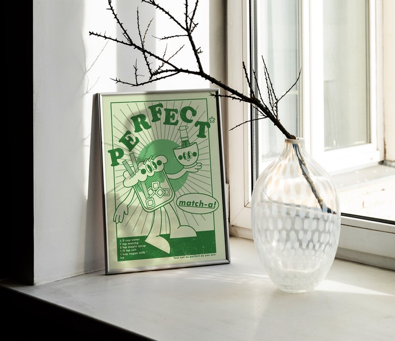 May include: A framed green and white poster with the word "PERFECT" in large letters. The poster features a cartoon illustration of a matcha drink and a bottle, with the text "match-a!" and a recipe at the bottom.