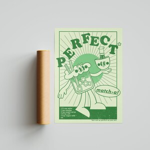 May include: A light green poster with a retro cartoon design promoting matcha. The poster features a character holding a matcha drink and a bowl. Text includes "PERFECT" and "match-a!" with a recipe. A brown cylindrical tube is next to the poster.