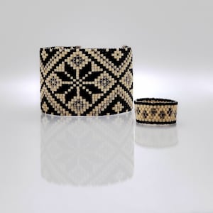 May include: A black and white beaded bracelet and ring set with a geometric pattern. The bracelet is wide and the ring is thin.