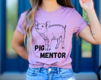 Könnte beinhalten: Ein helllila T-Shirt mit einer Schwarzweißillustration eines Schweins und dem Text "Pig Mentor".