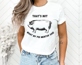 Könnte beinhalten: Weißes T-Shirt mit einer Schwarzweißillustration eines Schweins und dem Text "That's not what my pig mentor said."