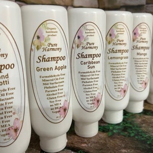 May include: A row of white shampoo bottles with oval labels featuring floral designs and the words "Pure Harmony Shampoo." Flavors include Almond Biscotti, Green Apple, Caribbean Sun, Lemongrass, Mango, and Apricot. Each bottle is 10 fl oz.