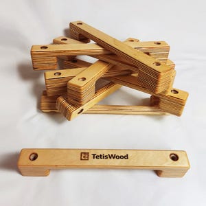 May include: A stack of six wooden handles with rounded edges and a single handle with the text "TetesWood" on the top. The handles are made of light brown wood and have a natural finish.