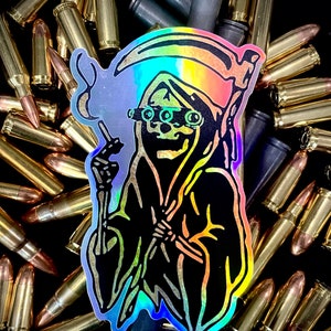 May include: A holographic sticker depicting the Grim Reaper with a scythe, wearing goggles, and smoking. The sticker is set against a backdrop of bullets, creating a dark and edgy aesthetic.