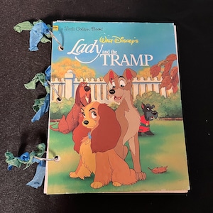 May include: A Little Golden Book featuring Walt Disney's Lady and the Tramp. The cover shows Lady, Tramp, and two other dogs in a green grassy area with a white picket fence in the background.