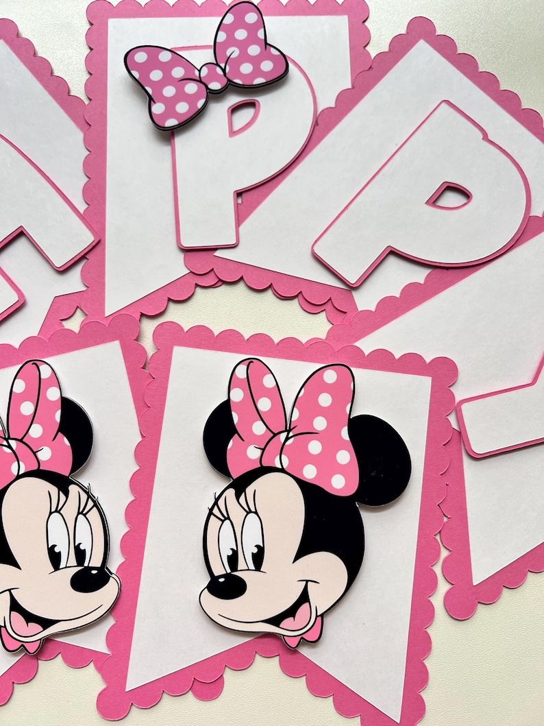 May include: Pink and white banner with a scalloped edge. The banner features a Minnie Mouse character with a pink bow and white polka dots. The banner also has the letter "P" in white with a pink outline.
