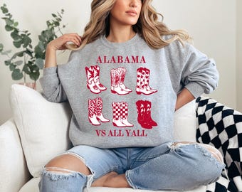 May include: Gray sweatshirt with a red graphic of cowboy boots and the text "ALABAMA VS ALL YALL".