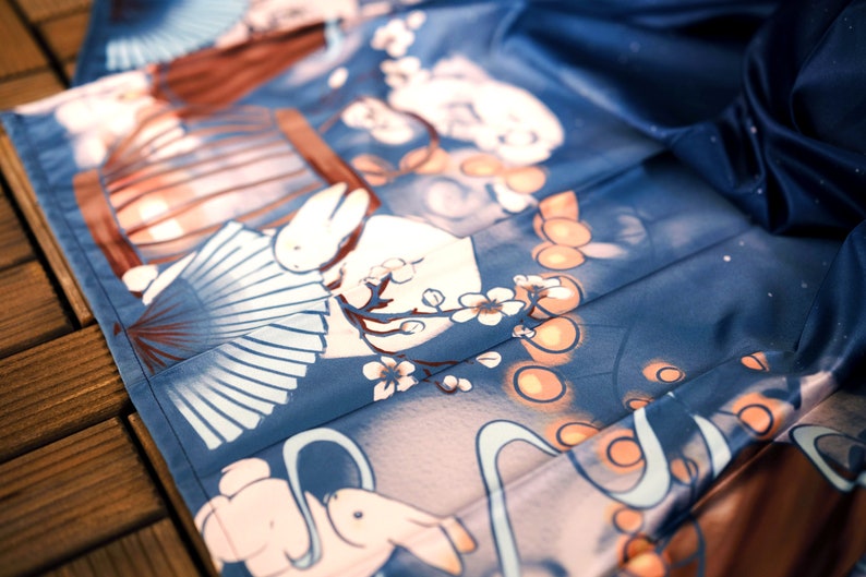 May include: A blue fabric with a white rabbit and a fan design. The fabric has a light blue and white floral pattern with orange circles.