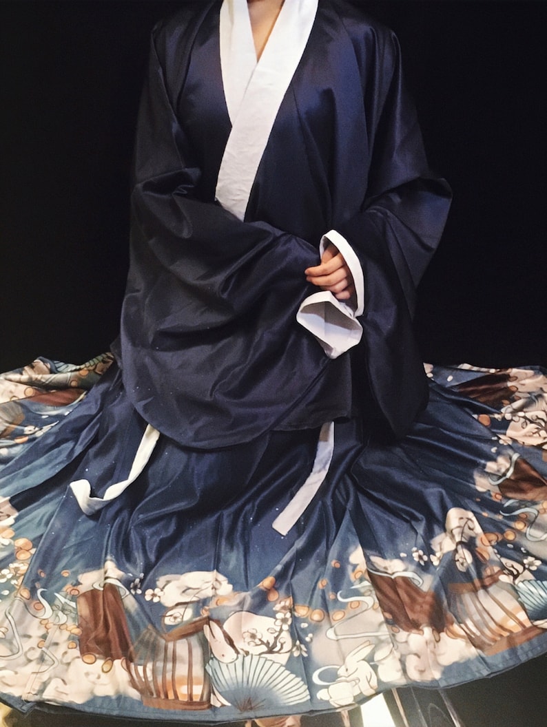 May include: A navy blue and white traditional Chinese dress with a long skirt featuring a pattern of white rabbits, clouds, and lanterns. The skirt is made of a silky fabric.