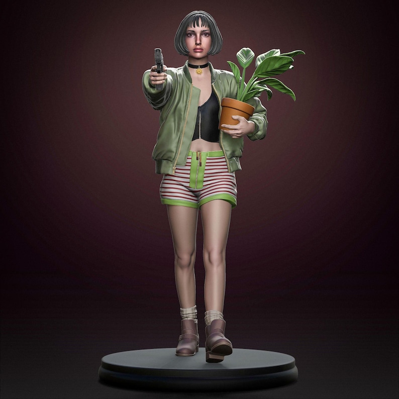 May include: A detailed figurine of a woman holding a gun and a potted plant. She wears a green bomber jacket, striped shorts, and boots. The figure stands on a black circular base against a dark background. The woman has short dark hair and a choker.
