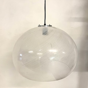 May include: A white glass globe pendant light with a black cord and a silver metal ceiling fixture. The globe has a white striped pattern.