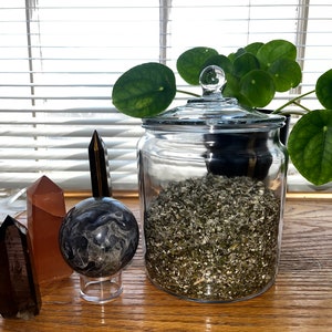 May include: A glass jar filled with dried herbs, a black and white marble sphere on a stand, and a few crystals on a wooden surface.