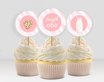 May include: Three cupcakes with white frosting and colourful sprinkles. Each cupcake has a pink and white striped topper. One topper has a cookie, one says "tough one", and the last has a milk bottle.