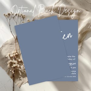 Peut inclure: Deux cartons d'invitation bleus avec du texte blanc, dont un partiellement visible. Le texte "Optional Back Design" est en haut. La deuxi&egrave;me carte porte le nom "en" et les d&eacute;tails de l'&eacute;v&eacute;nement. Des fleurs s&eacute;ch&eacute;es et un tissu beige sont en arri&egrave;re-plan.
