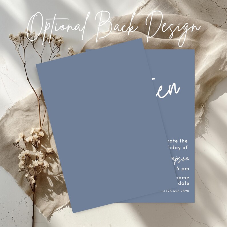 Peut inclure: Deux cartons d'invitation bleus avec du texte blanc, dont un partiellement visible. Le texte "Optional Back Design" est en haut. La deuxi&egrave;me carte porte le nom "en" et les d&eacute;tails de l'&eacute;v&eacute;nement. Des fleurs s&eacute;ch&eacute;es et un tissu beige sont en arri&egrave;re-plan.