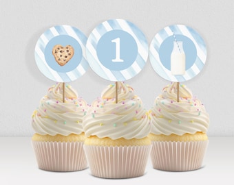 May include: Three cupcakes with white icing and colourful sprinkles. Each cupcake has a round topper with a blue and white striped background. One topper has a chocolate chip cookie, another has the number 1, and the last has a milk bottle.