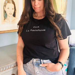 May include: A black t-shirt with white embroidery that reads "Vive La Resistance".