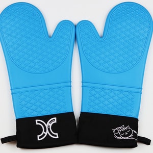 May include: A pair of bright blue oven mitts with a textured diamond pattern on the front. The mitts have black cuffs with a white logo and a sleeping cat graphic. Each mitt has a loop for hanging.