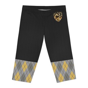 May include: Black leggings with a yellow and gray argyle pattern at the bottom. A small pocket on the right side features a badger graphic.