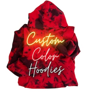 May include: Red and black tie-dye hoodie with a hood and front pocket. The words "Custom Color Hoodies" are written in a neon-style font across the front of the hoodie.