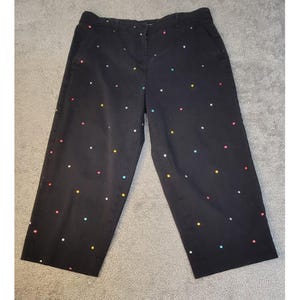 May include: Black cropped pants with colorful polka dots. The pants have a button and zipper closure, pockets, and a wide leg. The polka dots are in various colors, including red, yellow, blue, and white. The pants are made of a cotton blend.