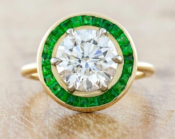 May include: A gold ring featuring a large, round, clear gemstone surrounded by a halo of emerald-green stones. The ring has a classic design with a polished gold band. The ring is a piece of jewelry.