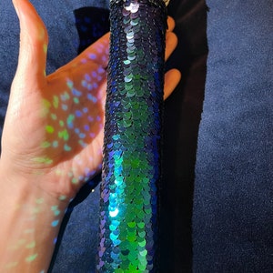 May include: A microphone covered in iridescent green and blue sequins.