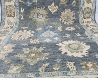 May include: A blue and beige patterned rug with a floral design. The rug has a fringe border.