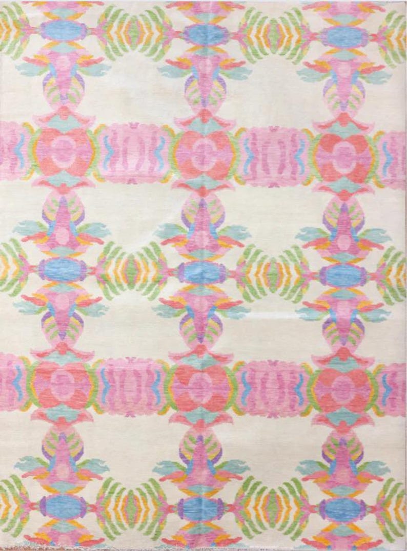 Handmade modern wool rug with pastel pink, lavender, blue, green, and yellow geometric botanical motifs on an ivory background.