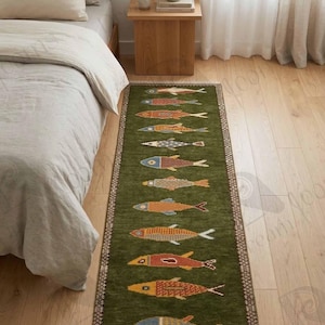 May include: A long, rectangular green rug with a repeating pattern of colorful fish. The fish designs feature various colors, including orange, red, and blue. The rug is placed on a wooden floor, and the edges have a decorative border.