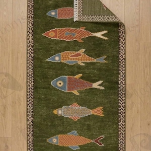 May include: A green rectangular rug with a repeating pattern of colorful fish. The fish are in shades of red, orange, blue, and yellow. The rug has a decorative border and fringe.