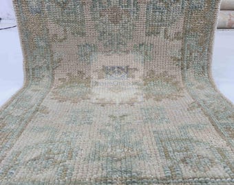 May include: A light green and beige patterned rug with a fringe border. The rug has a traditional design with a central medallion and repeating geometric patterns.