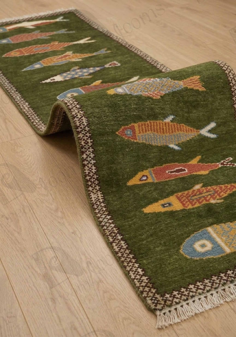 May include: A green runner rug with a repeating pattern of colorful fish. The fish are in shades of orange, yellow, blue, and red. The rug has a decorative border and is placed on a wooden floor.