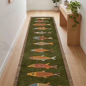 **Alt Text (SEO friendly):**

Handmade hand-knotted wool fish runner rug with colorful fish motifs on a deep green background and decorative border, coastal nautical hallway runner carpet with fringe. 🐟