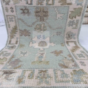 May include: A light blue and cream colored rug with a geometric pattern. The rug has a fringe border.