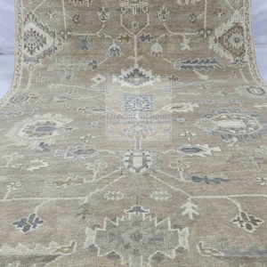 May include: A beige rug with a geometric pattern in shades of brown, gray, and white. The rug has a fringe border.