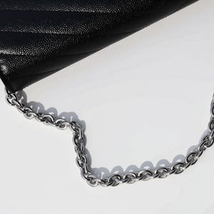 A black leather handbag with a silver chain strap is shown in the image.