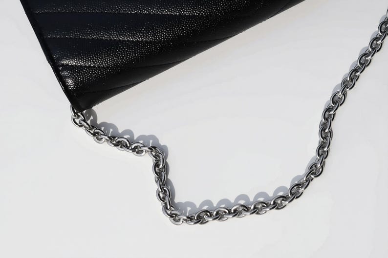 A black leather handbag with a silver chain strap is shown in the image.