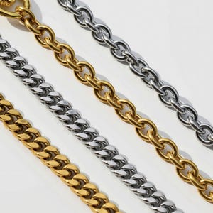 a close-up view of several metal chain necklaces with different colored links, including gold, silver, and white.