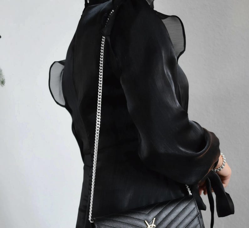 a woman in a black dress holding a black purse