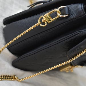 a black purse with a gold chain hanging from it