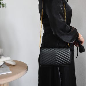 a woman in a black dress holding a black purse