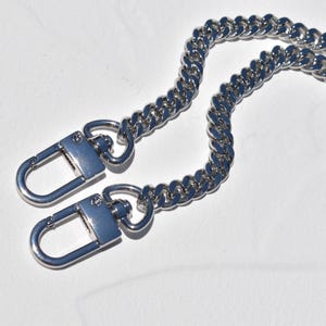 a close-up view of a silver chain necklace with two lock-shaped clasps.