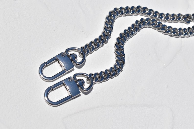a close-up view of a silver chain necklace with two lock-shaped clasps.