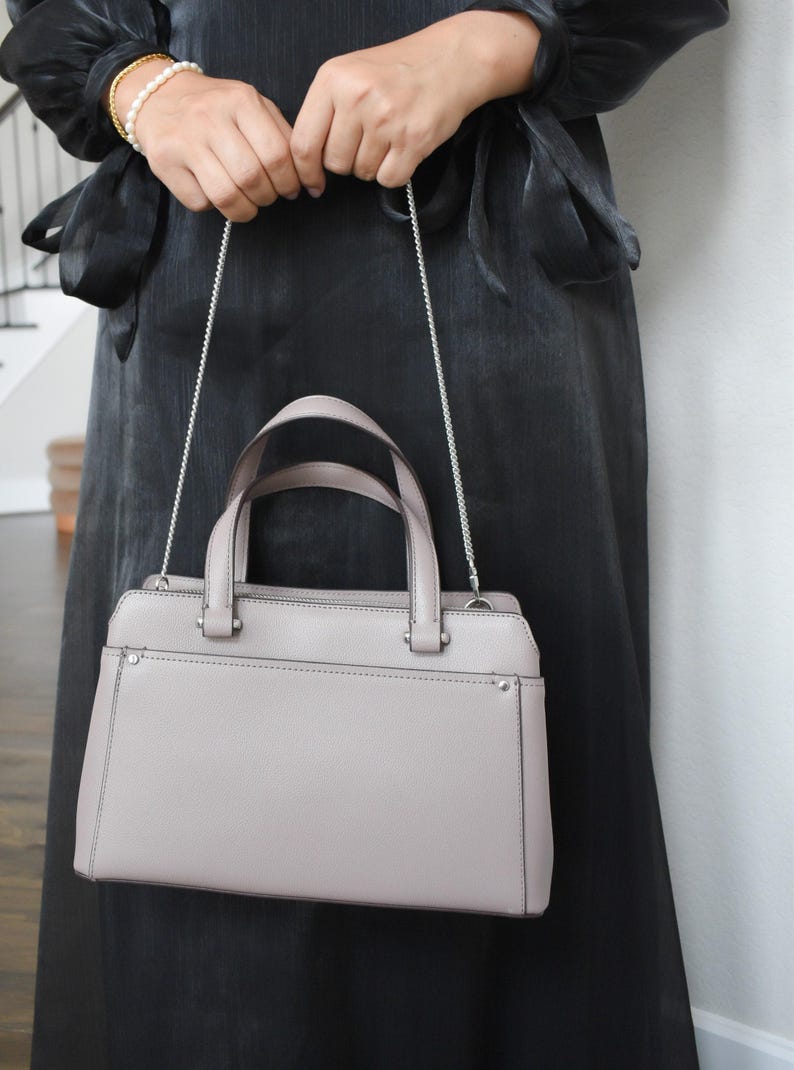 a woman in a black dress holding a gray purse