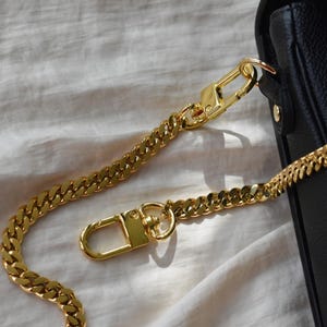 a gold chain is attached to a black purse