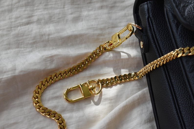 a gold chain is attached to a black purse