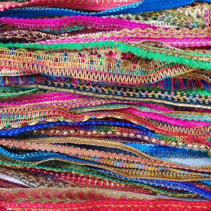 May include: Assortment of colorful trim and ribbon with various textures and embellishments, including sequins, beads, and fringe.